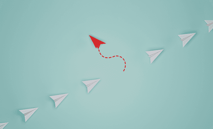 Paper airplanes with a red one that is taking a different trajectory.