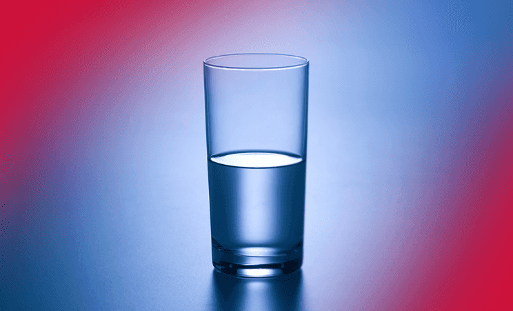 Glass of water half full or half empty. Red and blue gradient background.