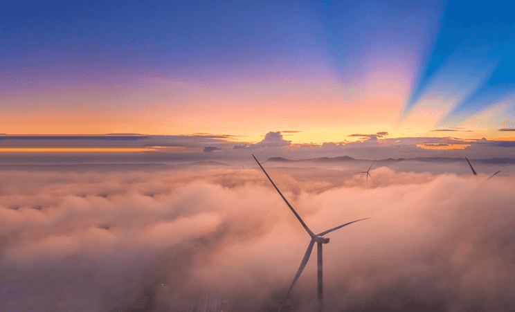 Windmills above clouds during a sunset